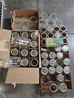 Overview of all mason jars and lids arranged inside boxes, showing several glass jars and caps in different styles and shapes.