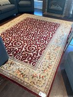 Full view of rectangular wool area rug with maroon and yellow floral design in a living room setting.