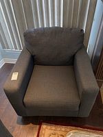 Front view of the grey upholstered arm chair, showing the full seat and back cushions and armrests.