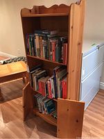 Full view of wooden bookshelf with shelves holding books, and bottom doors open revealing space.