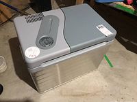 Top and side profile view of cooler showing integrated ventilation fan on gray lid and metallic silver body with horizontal ridges.