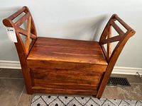 Full frontal view of the solid wood entry bench showing the hinged top and X backrest design on the sides.