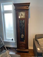 Full height wooden grandfather clock with decorative carvings, paw-foot base