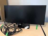 Front view of 34" monitor on desk with stand and coiled cable