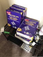 Photo showing multiple reams of Staples multipurpose bright white copy paper stacked on a black mesh shelving unit.