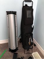 Silver cylindrical speaker unit and black carrying bag on wheeled trolley
