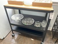 Front view of rolling utility cart showing plywood top and two black metal shelves with glassware staging removed