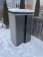 Angled front-left view of assembled plastic shed standing in snow