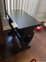 Black Ashley Furniture side table with curved sides and magazine rack below