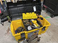 Opened yellow Strong N' Tuff 27 inch tool chest showing DeWalt chalk reel kit, two metal hand planes, measuring tape, hardware, and small tools inside.