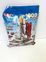 Front of sealed bag showing brand, 1000 pcs blocks, and space shuttle with launch tower model