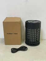 Photo showing mosquito zapper device, black USB cable, and brown branded box against a plain background.