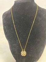 Gold-tone necklace displayed on black jewelry bust, showing pendant closed as a heart with subtle sparkle.