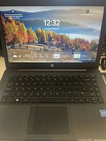 Front view of HP laptop screen displaying Windows 11 desktop with weather and time widgets