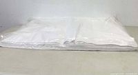 Photo of a large bundle of neatly stacked white tissue paper sheets in clear plastic wrapping on a table surface.