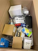 Top view of the box showing multiple boxed household items, electronic cables, smartphone case, tools, and small items