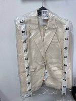 Front view of off-white linen blazer in original packaging showing the one-button closure and notched lapels.