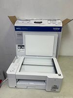 Opened multifunction printer showing the scanning bed and control panel.