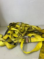 Overall view of two yellow ratchet straps with metal ratchet buckles and hooks lying on a flat surface.
