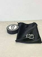 Photo of NHL hockey puck with portrait of Robert Gordon (Bobby Orr) and black drawstring pouch with NHL logo