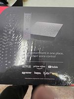 Box front showing image of streaming device and remote with logos of supported streaming services including Netflix, Prime Video, YouTube, STV NOW, hayu, Tubi