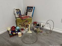 Multiple items arranged against wall showing boxes of ornaments, roller coaster display box, ceramic items, electric candle and platter