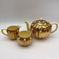 Photo showing the full vintage Gibsons tea set including the tea pot, creamer and sugar bowl all in gold with yellow polka dots.