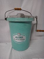 Full view of assembled vintage 1950s Alaska Hostess ice cream freezer bucket with metal lid and wooden crank handle.