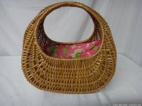 Front view of the wicker basket purse showing the natural brown woven texture and integrated handles, interior pink floral fabric lining visible.