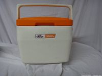 Front view of the cooler showing the white textured plastic body and bright orange lid with a sturdy white handle.