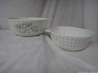 Two white glass Pyrex casserole dishes side by side, each with different floral pattern.