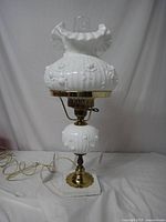 Full view of vintage milk glass table lamp showing ruffled shade, brass fittings, and marble base with attached cord.