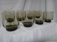 Eight vintage tawny brown Libbey rock glasses arranged on white fabric background showing uniform size and color.