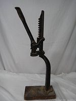 Front and side views of the cast iron antique bottle capper/corker, showing lever, serrated bar, and base.