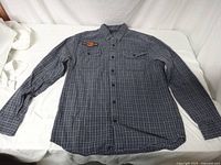 Full front view of the shirt laid flat showing button-up closure, checkered pattern, and Harley Davidson patch on left chest