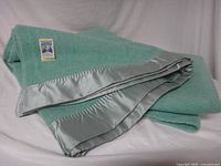 Folded green wool blanket showing satin border