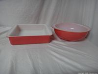 Image showing the 8-inch square baking dish and the 8.5-inch round casserole dish from side front view on a white fabric background.