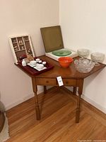 Corner wood table with assorted decorative items arranged on top and leaning against the wall