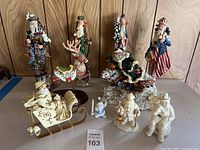Full view of all holiday-themed figurines including plush sleigh with Santa, reindeer, bagpipe Santa, patriotic Santa, and smaller porcelain Santas.