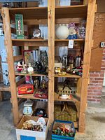 Full view of wooden shelving unit with multiple shelves showing a variety of vintage holiday decor and miscellaneous household items including Santa figurines, holiday figurines, trays, and kitchenware items.