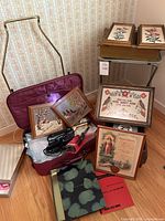 Photo capturing vintage framed needlepoint pictures, rolling luggage, TV trays, framed documents and hair styling tools.