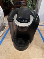 Front view of the black and silver Keurig coffee machine showing the brand label and drip tray.