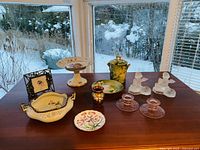 Photo showing all items on table including the angel candle holders, rose glass holders, raised tray with pineapple, green dish and pot with lid, floral jar, pewter picture frame, ornamental bowl, and ring plate.