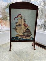 Full view of the framed needle art featuring the ship displayed indoors near window light.