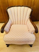 Front view of the armchair showcasing scallop pattern upholstery and carved wood frame