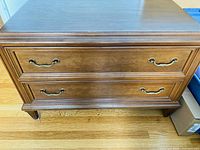 Front view showing two wide drawers with brass-colored handles, wood grain visible.