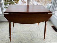 Front view with both leaves folded, showing compact profile and turned legs