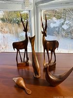 Front angle showing all five wooden animal sculptures on a table by the window with winter scenery outside.
