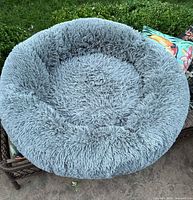 Full top-down view showing gozy grey fluffy donut dog bed with thick sides and padded middle, resting on outdoor furniture.