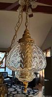 Clear textured glass globe with leaf pattern and ornate gold metal fittings, hanging chain visible